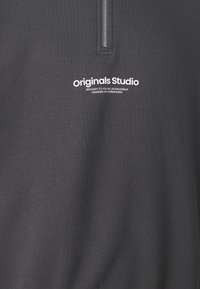 Dunkelgrauer Pullover mit einem halben Reißverschluss, der ein weißes "originals Studio"-Logo und Text auf der Vorderseite zeigt; besteht aus einem weichen, strukturierten Material.