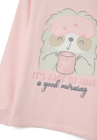 Top de manga larga rosa claro con un dibujo de un perezoso que lleva un antifaz de dormir y sostiene una taza rosa. El texto dice: "ES FÁCIL TENER una buena mañana."