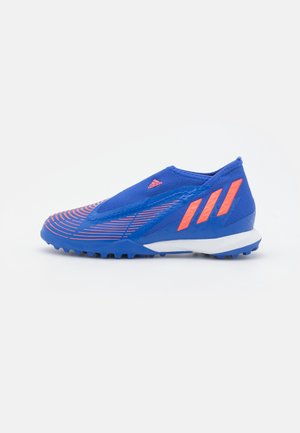 Chaussure de football Adidas bleue et orange avec tige texturée et crampons en caoutchouc sur la semelle, conçue pour jouer sur sol dur.