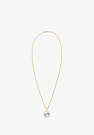 Collar de cadena de oro con un pendant floral que presenta un diseño en blanco y negro, usado con un suéter beige que resalta el escote.