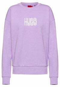 Sudadera morada de tejido suave, con cuello redondo y puños acanalados. En la parte frontal muestra un logotipo blanco "HUGO" en un diseño curvado.
