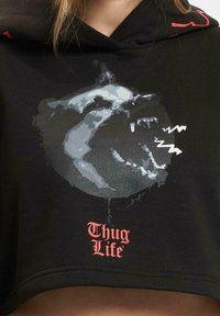 Black cropped hoodie featuring a graphic of a bear's face, with gray and white accents. "Thug Life" text in red at the bottom.