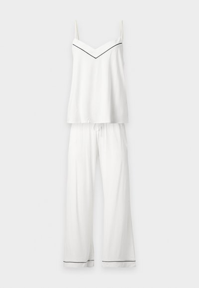 Ensemble pyjama blanc deux pièces avec top à bretelles fines spaghetti et pantalon à jambes larges, avec une fine bordure noire sur le décolleté et les ourlets du pantalon.