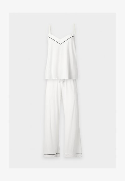 Ensemble pyjama blanc deux pièces avec top à bretelles fines spaghetti et pantalon à jambes larges, avec une fine bordure noire sur le décolleté et les ourlets du pantalon.