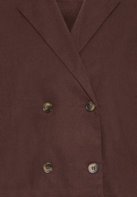 Blazer marron foncé à double boutonnage avec de larges revers et quatre boutons foncés disposés en deux rangées verticales.