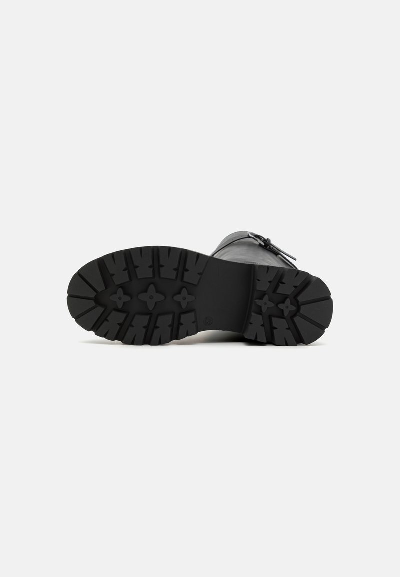 Schwarze Schuhsohle, strukturiertes Gummi mit tiefen Profilen für besseren Halt, abgerundete Form, glattes Obermaterial, ausgestattet mit verstellbarem Schnallen-Detail.