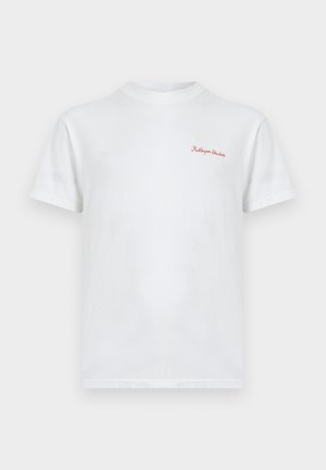 Tricou alb din bumbac cu gât rotund și mâneci scurte, având text roșu brodat "KidSuper Studio." Textură netedă, croială standard.