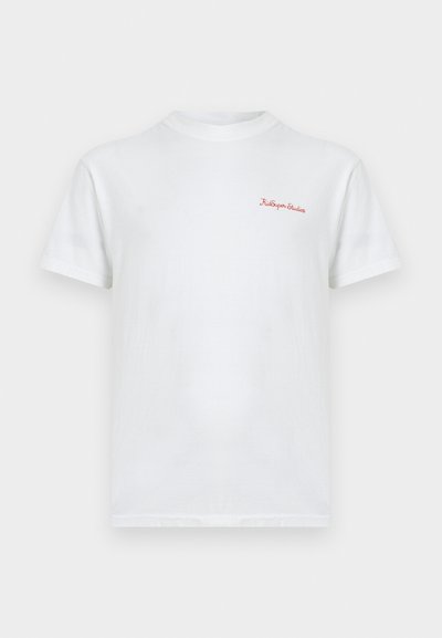 Λευκό βαμβακερό t-shirt με στρογγυλή λαιμόκοψη και κοντά μανίκια, με κόκκινη κεντημένη επιγραφή "KidSuper Studio." Ομαλή υφή, κανονική εφαρμογή.