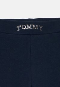 Marinblå leggings har et mykt stoff med en tettsittende design og en metallisk sølv "TOMMY" logo på livet.