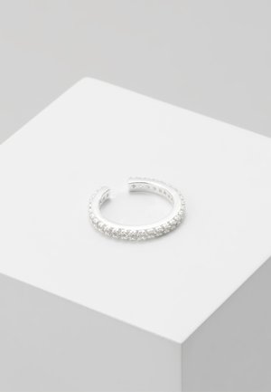 Silberner offener Ring, verziert mit zwei Reihen kleiner runder klarer Edelsteine, präsentiert auf einem weißen quadratischen Podest.