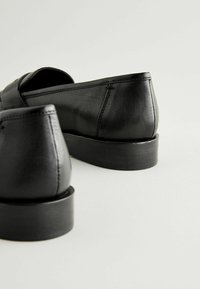 Sorte læder loafers med en glat finish, lav stakket gummihæl og diskrete syninger på siderne.