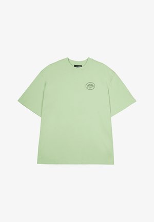 Lys grønn kortermet t-skjorte i bomull med rund hals og en liten svart logo trykket på venstre bryst.