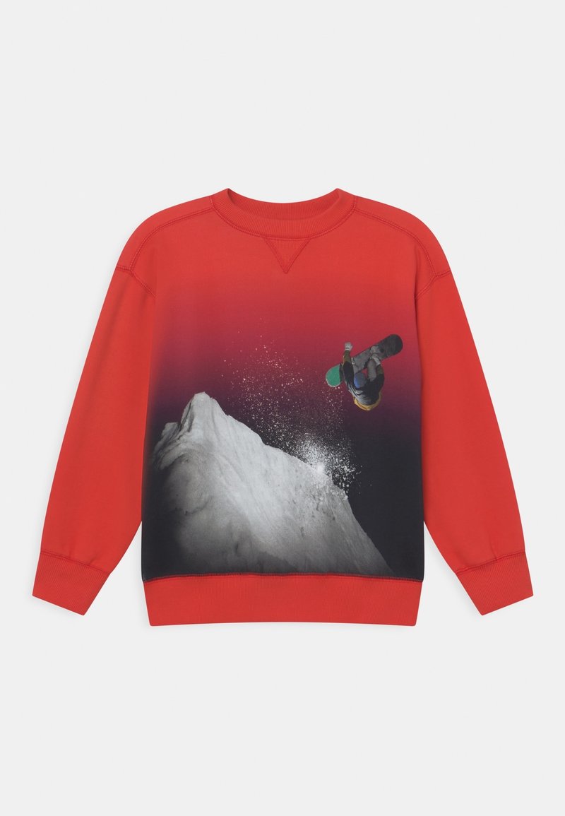 Sweatshirt rouge avec un design dégradé, mettant en avant un snowboarder noir et blanc sautant au-dessus d'un sommet enneigé, montrant texture et couleurs vives.