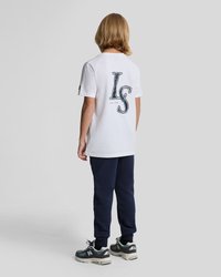 Balta medvilnė marškinėliai su mėlyna "LS" grafika ant nugaros, derinami su tamsiai mėlynais treniruokliais ir juodais/pilkais sportiniais bateliais.