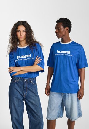 Blå kortärmade skjortor med en texturerad design, med "hummel PERFORMANCE" i vitt. En modell bär jeansshorts, den andra ljusblå shorts.