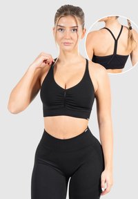 Sostenedor deportivo negro con escote en forma de U, detalle fruncido en el frente y tirantes estrechos ajustables con diseño de espalda de nadador.