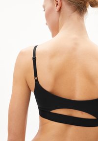 Zwarte sportbh met verstelbare bandjes, voorzien van een U-vormige ruguitsnede en een gladde textuur, ontworpen voor comfort en flexibiliteit.