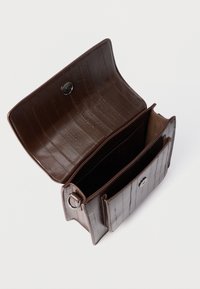 Portofel maro din piele cu un model texturat de crocodil. Dispune de un sistem de închidere cu capsa și două compartimente. Interiorul este neted și simplu, fără ornamente.