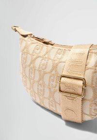 Beige fabric crossbody bag with embossed logo pattern, gold hardware, and a textured strap. Features a zip closure and curved shape.