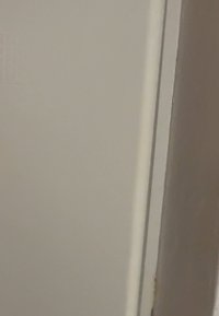 White interior door with a smooth surface, featuring subtle texture, thin frame, and minimal hardware. The edge shows slight wear.