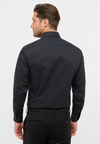Zwarte shirt met witte stippen, regular fit, lange mouwen en een klassieke kraag. Voorzien van knopenmanchetten en een gladde stof.