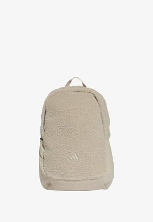 Mochila beige con un panel frontal de felpa suave, sección inferior lisa y un asa superior para llevar. Presenta un discreto detalle de logotipo en la parte inferior.