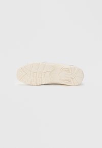 Podešev boty s texturovaným povrchem, s hlubokými vzory dezénu a světle krémovou barvou. Obsahuje značení v červených a modrých akcentních barvách.