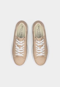 Ζευγάρι μπεζ σουέντ αθλητικά παπούτσια με λευκά κορδόνια και σόλες, απόψης από πάνω, με τη μάρκα Marc O'Polo στο εσωτερικό του παπουτσιού.