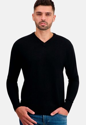 Schwarzer V-Ausschnitt-Pullover aus Strickstoff, mit langen Ärmeln, gerippten Bündchen und Saum, getragen über blauen Jeans.