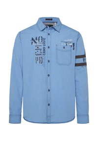 Camisa de botón de manga larga azul claro con estampados gráficos, bolsillo en el pecho y detalles de franjas negras en las mangas. Presenta un cuello con solapa.