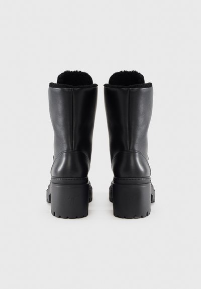 Czarne skórzane botki za kostkę z teksturowaną cholewką, podszewką z sztucznego futra oraz grubymi gumowymi obcasami z wyraźnym wzorem bieżnika.