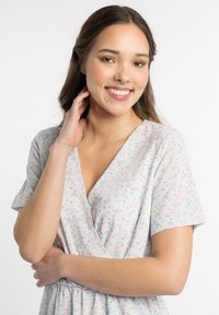 Robe bleu clair à manches courtes, avec un motif floral rose et vert, un col en V et une taille froncée pour une silhouette ajustée.