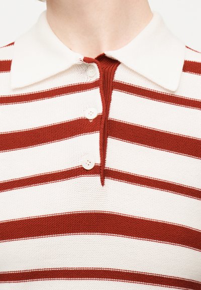 Polo tricoté à rayures blanches et rouge rouille avec trois boutons blancs et un col plié, porté autour du cou et du haut de la poitrine d'une personne.