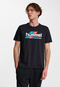 Czarny bawełniany t-shirt z kolorowym logo "hummel" z niebieskimi, czerwonymi i białymi akcentami. Okrągły dekolt i krótkie rękawy.