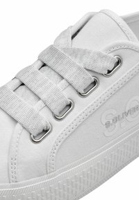 Sneaker bianco in tela con suola in gomma texturizzata, occhielli in argento e lacci piatti in cotone. Presenta un marchio discreto sul lato.