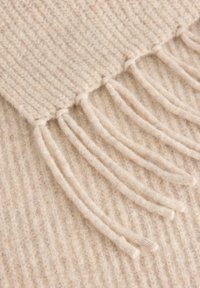 Beige ribbet tørklæde med frynset kanter lavet af blødt, struktureret materiale, der fremhæver en lys, naturlig farve.