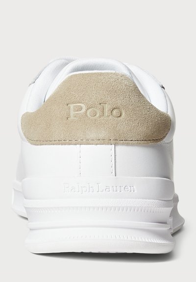 Valged spordijalatsid, mille beezist nahast kannaosa peal on kujutatud "Polo" ja valge tallaga, mille peal on kujutatud "Ralph Lauren", vaadatakse selja tagant.