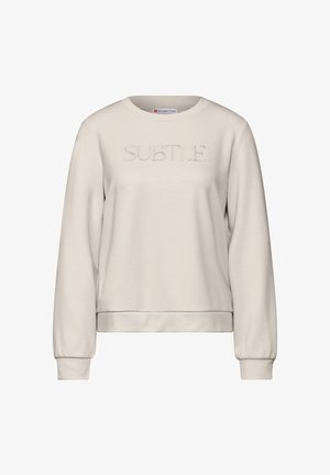Jasno beżowa bluza wykonana z miękkiego materiału, z teksturowanym nadrukiem "SUBTLE" na przodzie, okrągłym dekoltem i ściągaczami przy rękawach.