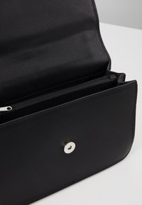 Portafoglio in pelle nera con una texture liscia, dotato di chiusura a scatto argentata e numerosi scomparti, incluso un taschino con cerniera.