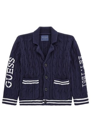 Granatowy kardigan na guziki z dzianiny warkoczowej, z białymi paskowanymi mankietami i kieszeniami, z napisem "GUESS" na lewym rękawie oraz "EST. 1981" na prawym rękawie.