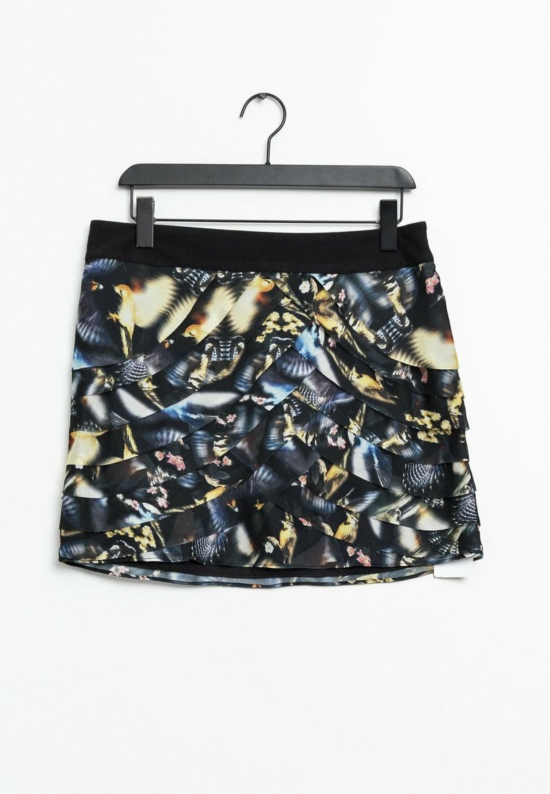 Jupe noire à volants superposés avec un motif abstrait multicolore de plumes d'oiseau, suspendue à un cintre noir.
