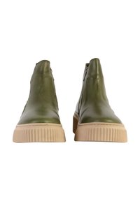 Botas de tobillo de cuero verde con una suela de goma texturizada de color marrón claro, que presentan un diseño elegante y cremalleras laterales para facilitar su uso.