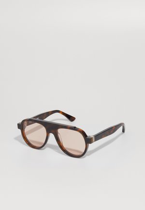 Brown tortoiseshell sunglasses with oval lenses, thick frame, and subtle hardware accents. Lenses are pink-tinted and semi-transparent.