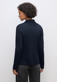 Marineblaue Langarmbluse mit Kragen, aus weichem Stoff mit strukturiertem Finish. In einer lässigen Passform und mit verlängertem Rückenteil gearbeitet.