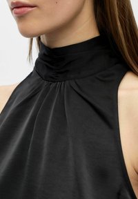 Schwarzes ärmelloses Top mit hohem Kragen und plissiertem Stoff mit glatter Textur. Entworfen mit einer figurbetonten Silhouette und eleganter Drapierung.