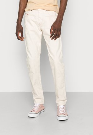 Pantalones de algodón de color beige claro con un corte relajado, que cuentan con bolsillos delanteros y un discreto detalle de logo bordado. Combinados con zapatillas rosas de corte bajo.