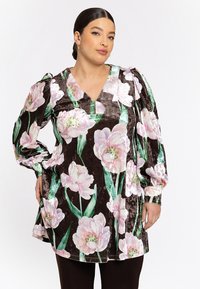 Fluwelen tuniek met een diepe V-hals, gekenmerkt door grote roze bloempatronen op een donkerbruine achtergrond en pofmouwen.