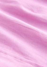 Helles rosa Gewebe mit einer glatten Textur, das subtile gewebte Muster und sanfte Falten zeigt. Die Oberfläche wirkt weich und leicht.