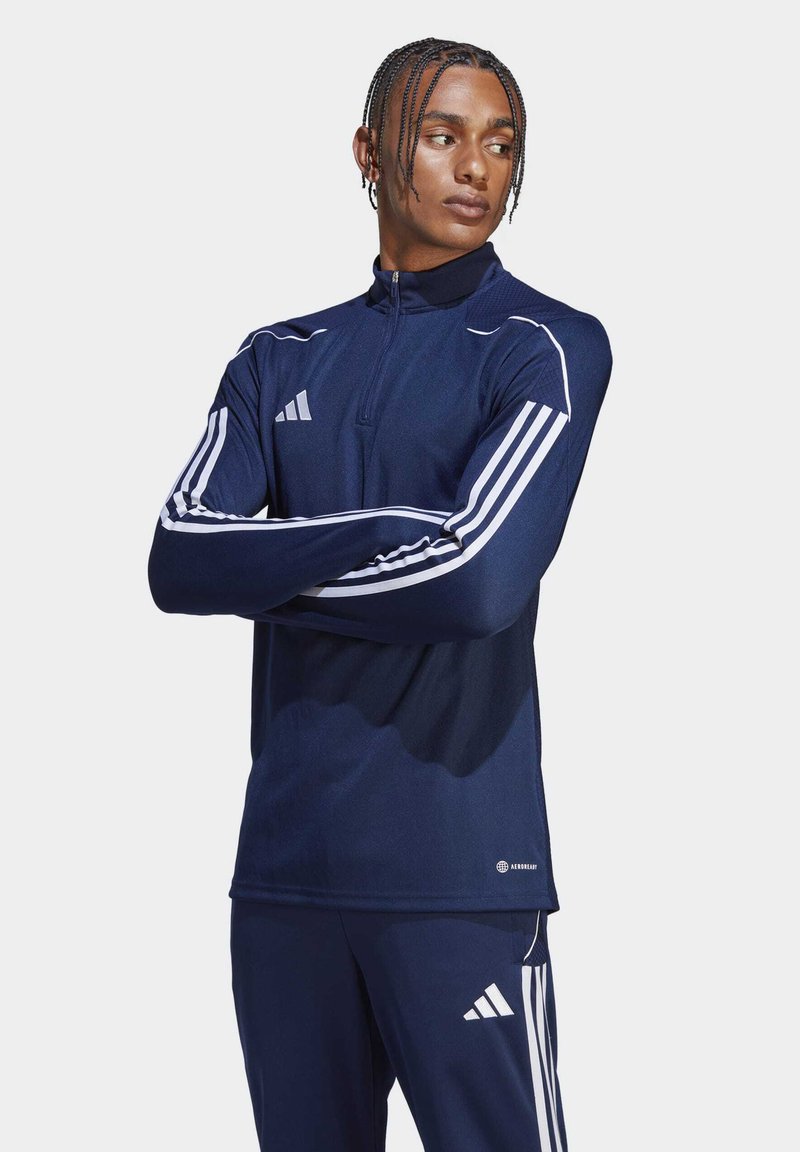 Felpa con zip blu marina, realizzata in tessuto traspirante, con strisce bianche sulle maniche e un logo audace sul petto.