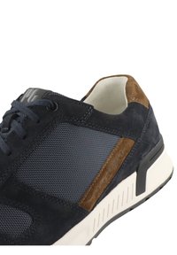 Dunkelmarineblaues Sneaker-Modell mit einer Kombination aus Wildleder und Mesh-Material. Braune Wildlederakzente. Weiße Sohle mit strukturierten Details. Schnürverschluss.